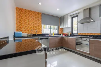 Modern kitchen with sleek cabinets, stainless steel appliances, and vibrant orange backsplash.