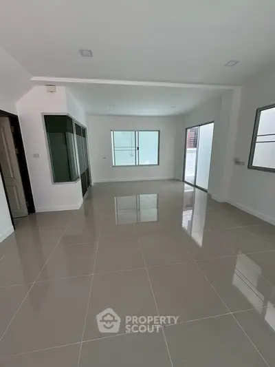 Spacious empty living room with large windows and glossy tiled floor