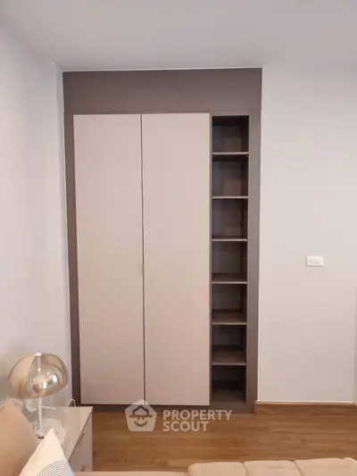 Modern bedroom with built-in wardrobe and stylish lamp on wooden floor.