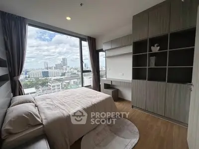 Modern bedroom with large window offering stunning city view, featuring sleek built-in storage and cozy decor.