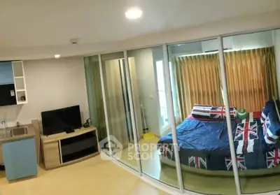 Modern studio apartment with glass partition, cozy bedroom, and compact kitchen area.