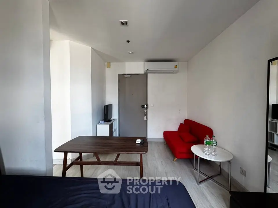 Modern studio apartment with minimalist furniture and bright red sofa