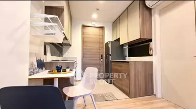 Modern kitchen with sleek cabinetry and dining area in compact apartment