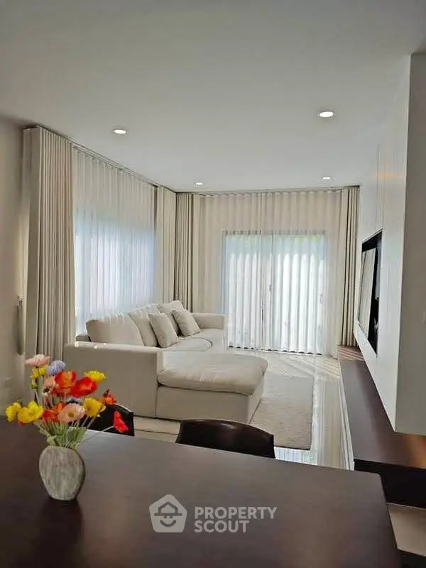 Elegant living room with cozy white sofa and large windows with sheer curtains