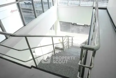 Modern staircase with sleek metal railings and large windows for natural light.