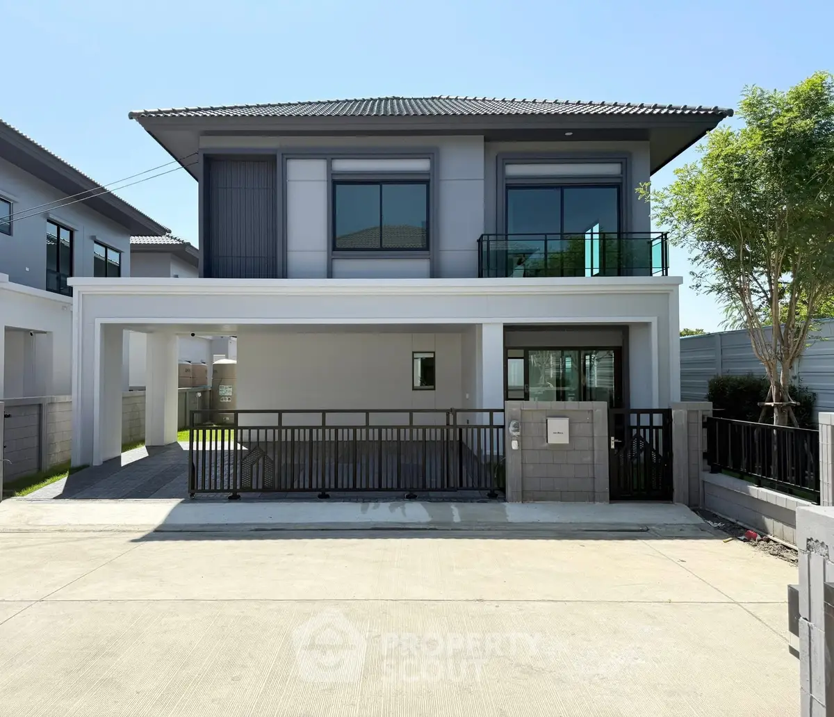 Modern two-story house with sleek design and spacious driveway in a suburban neighborhood.