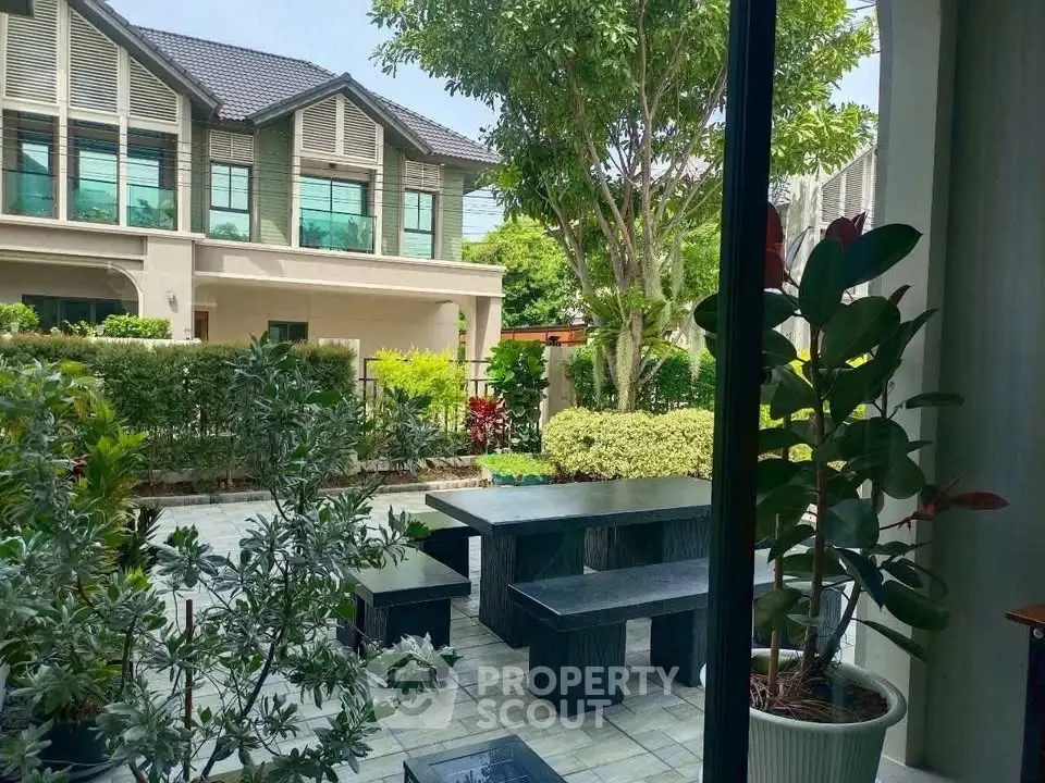 Charming garden view from modern home with lush greenery and stylish outdoor seating.