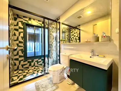Modern bathroom with geometric tiles and sleek fixtures, featuring a glass shower enclosure.