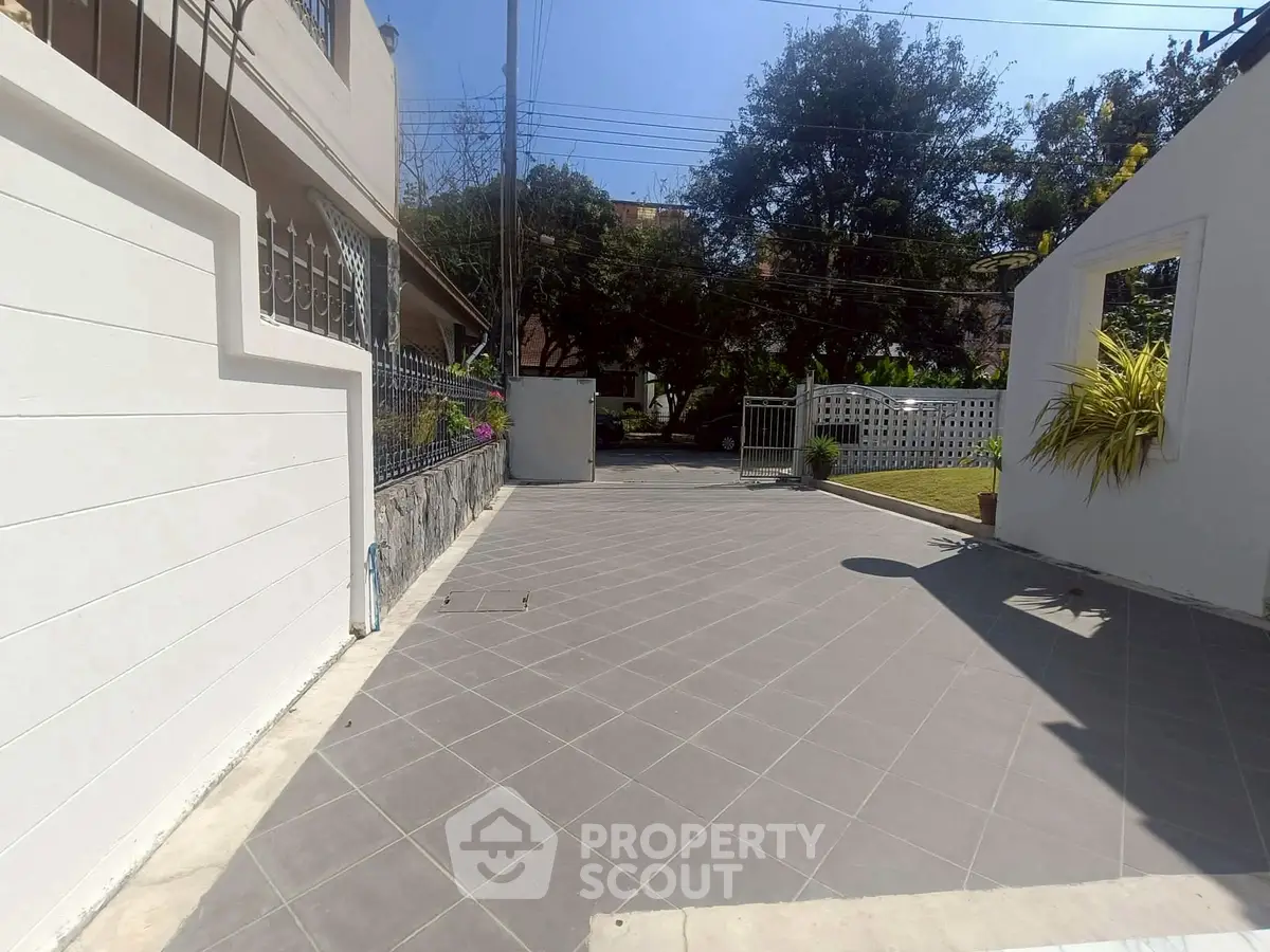 Spacious driveway entrance with modern tiled flooring and lush greenery