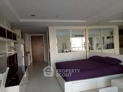 Modern studio apartment with sleek design and mirrored walls, featuring a cozy bed and ample storage.