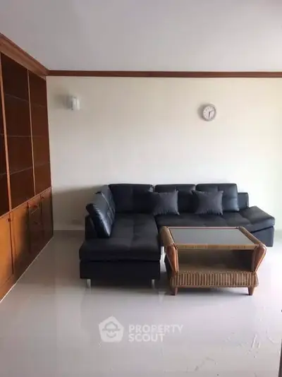 Spacious living room with modern black sofa and elegant wooden shelving