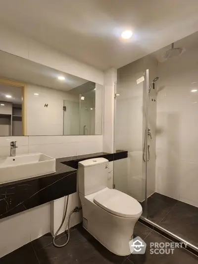 Modern bathroom with sleek design featuring glass shower and stylish fixtures.