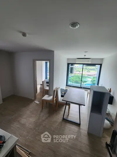Spacious living room with large window offering a stunning city view, perfect for modern urban living.