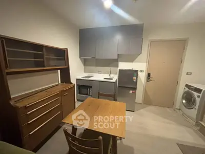 Cozy kitchen with modern appliances and wooden dining set in compact apartment.