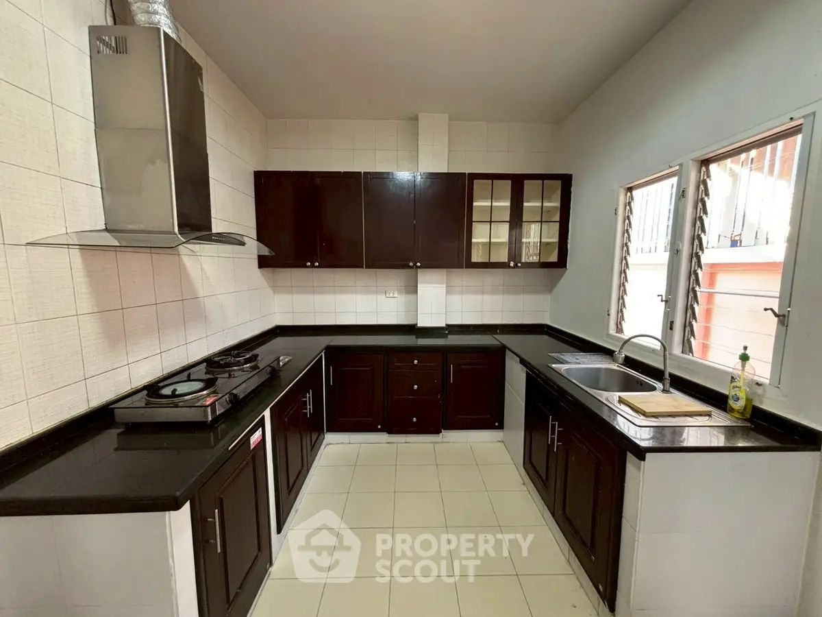 Spacious kitchen with dark wood cabinets and modern appliances in a bright, airy setting.