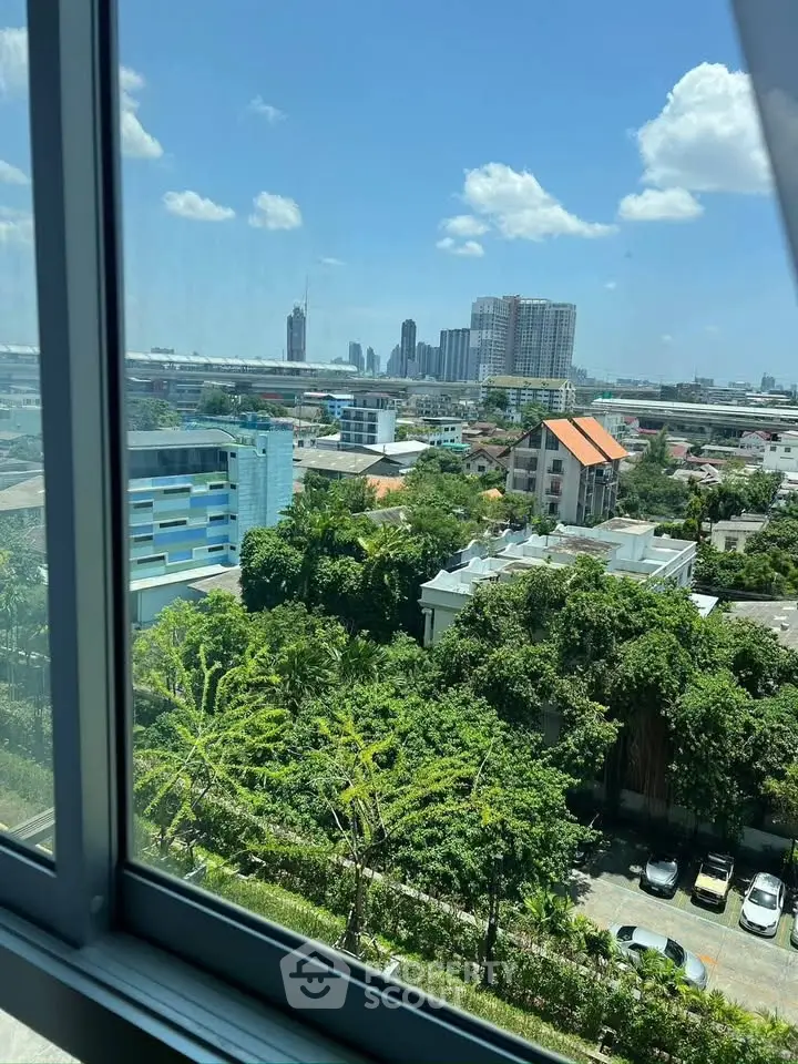 Stunning cityscape view from a high-rise window, showcasing lush greenery and urban skyline.