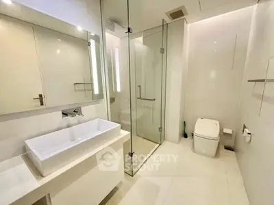 Modern bathroom with glass shower and sleek fixtures in luxury apartment.