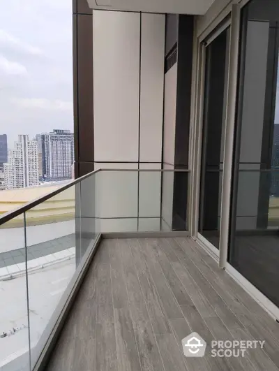 Modern balcony with glass railing and city view in high-rise apartment.