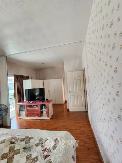 Spacious bedroom with wooden flooring and modern decor