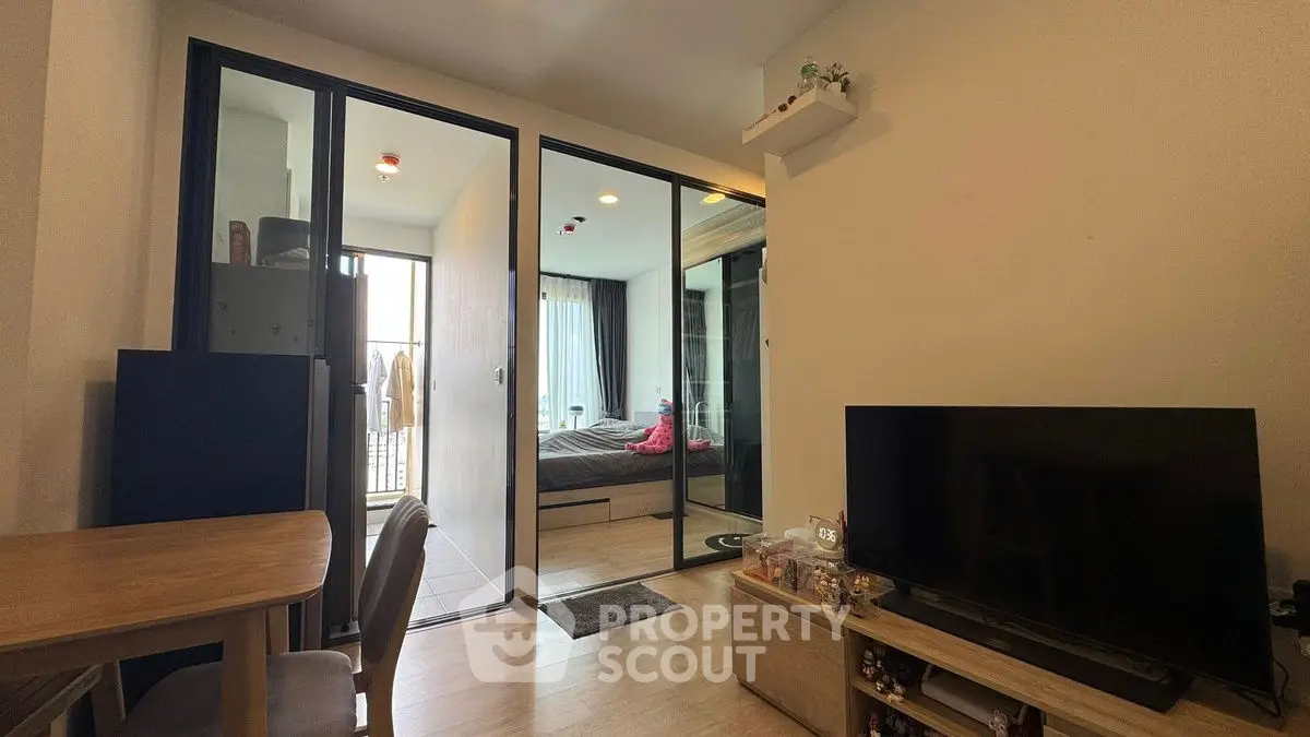 Modern apartment interior with open layout, featuring a cozy living area and bedroom with glass partition.