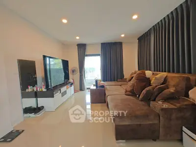 Spacious living room with plush brown sofa and large TV, perfect for relaxation.