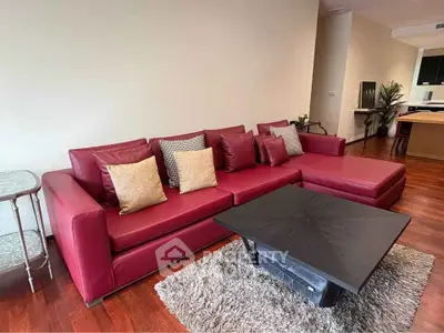 Stylish living room with red leather sofa and modern coffee table on wooden flooring.
