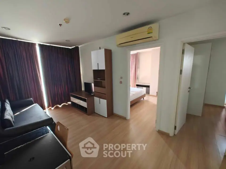 Spacious modern apartment with open living room and bedroom, featuring sleek wooden flooring and stylish furniture.