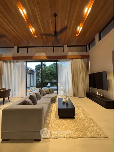 Luxurious modern living room with high wooden ceiling and large windows overlooking a serene garden.