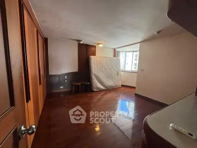 Spacious bedroom with wooden flooring and large window offering natural light.