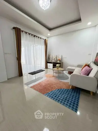 Elegant living room with modern decor and large window, featuring cozy seating and stylish rug.