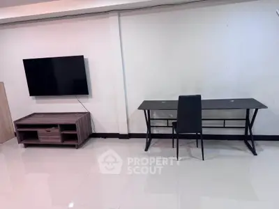 Modern minimalist living room with sleek TV setup and stylish desk area.