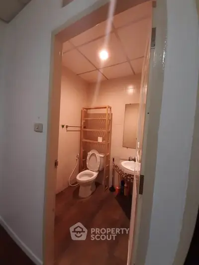 Cozy bathroom with modern fixtures and wooden shelving, perfect for compact spaces.
