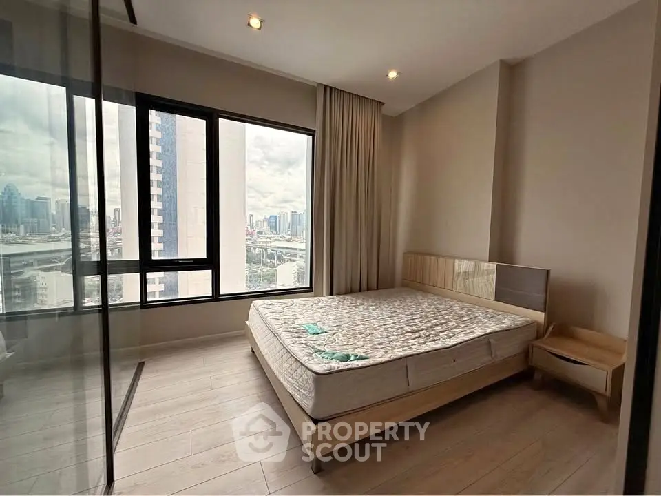 Modern bedroom with city view, large windows, and minimalist design in high-rise apartment.