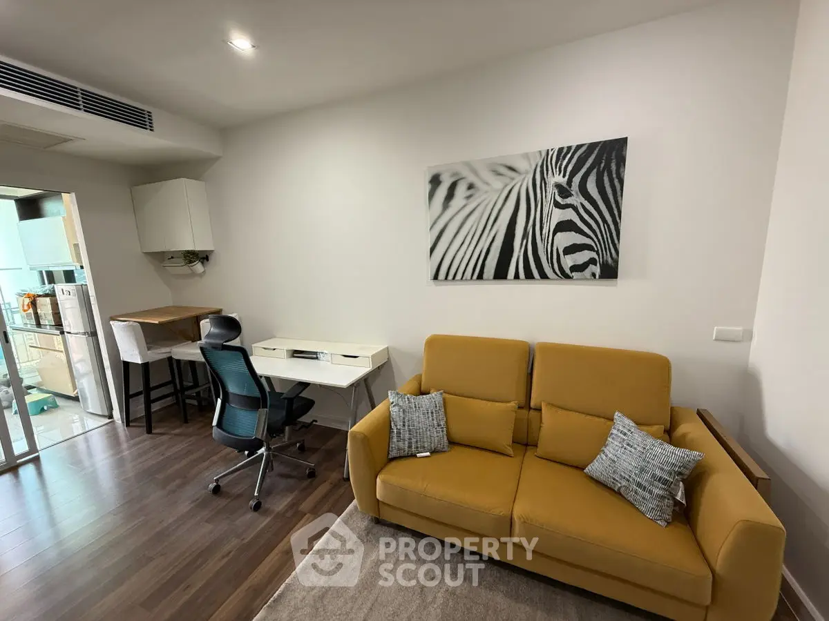 Modern living room with stylish decor and open kitchen layout, featuring a cozy yellow sofa and zebra artwork.