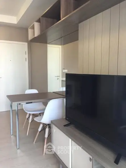 Modern living room with sleek furniture and wall-mounted storage, featuring a flat-screen TV and dining area.