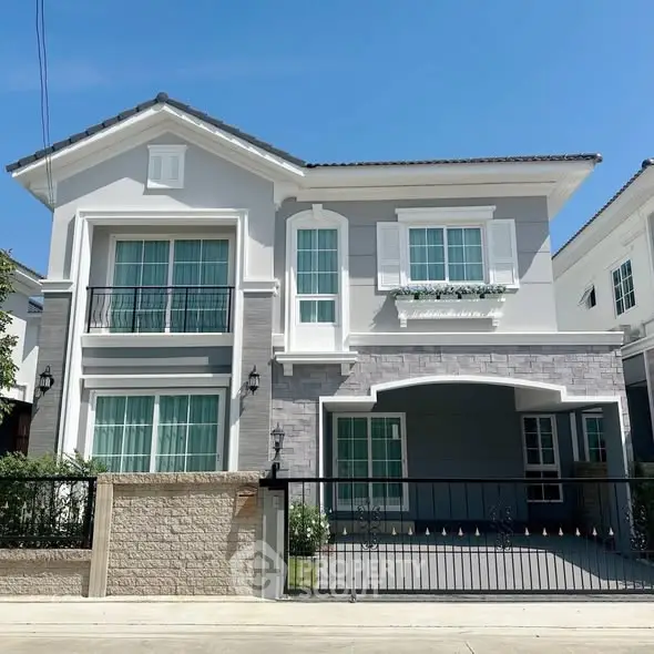 Elegant two-story house with modern facade and gated driveway in sunny neighborhood.