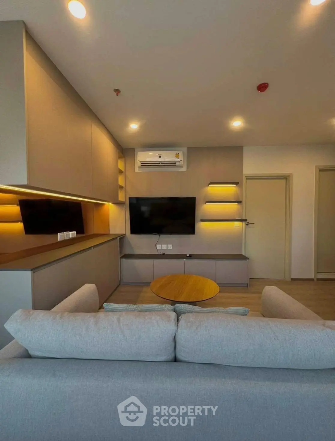 Modern living room with sleek design, featuring built-in shelves and a wall-mounted TV.