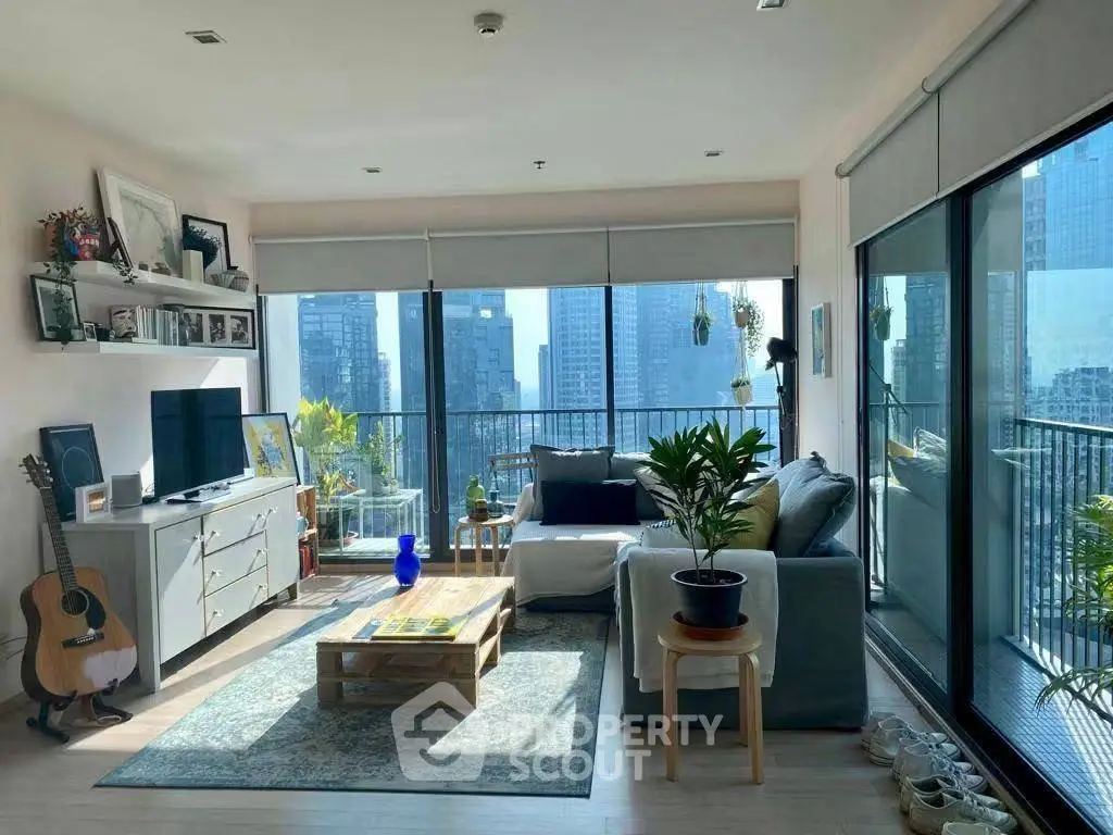 Spacious living room with large windows and city view, featuring modern decor and a cozy atmosphere.