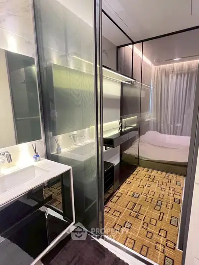 Modern bathroom with sleek design and glass partition leading to a cozy bedroom.