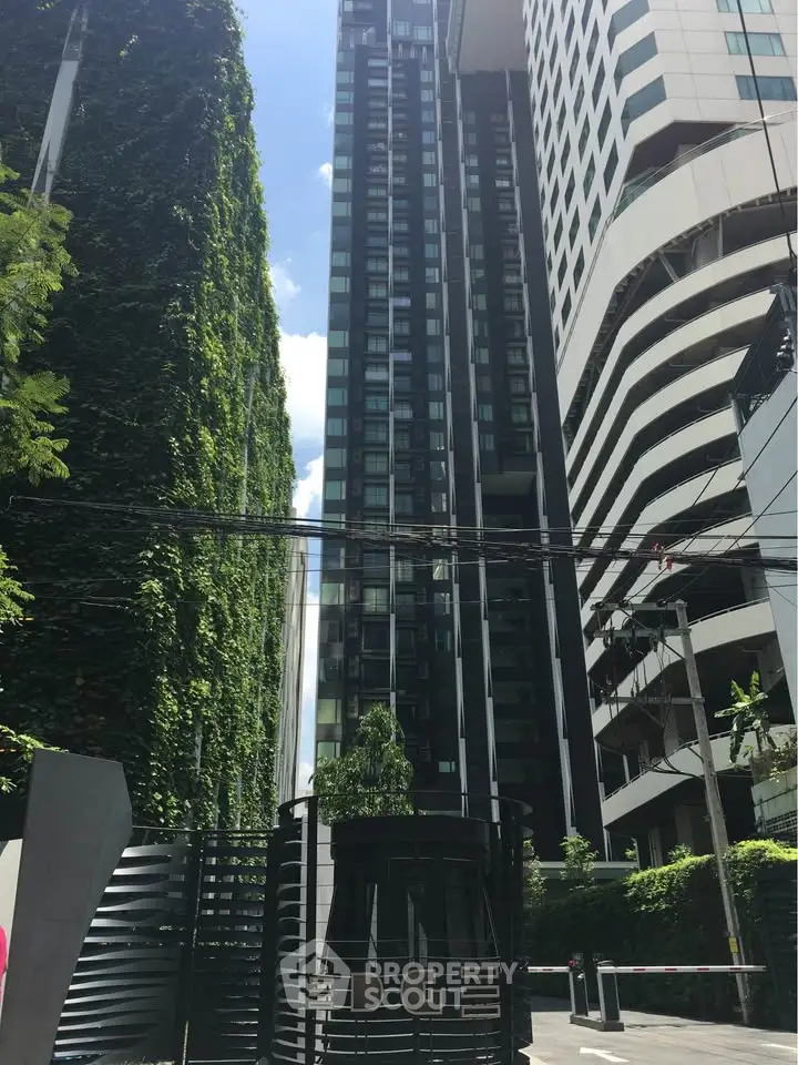 Modern high-rise building with lush greenery and sleek design in urban setting.
