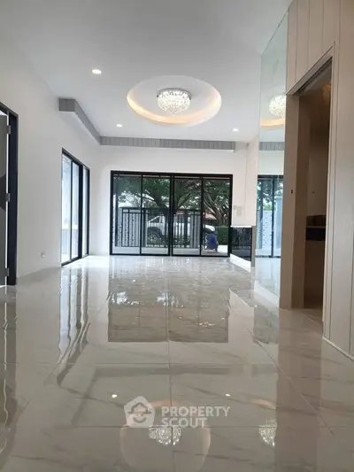 Spacious modern living room with glossy marble floors and large windows opening to a garden view.
