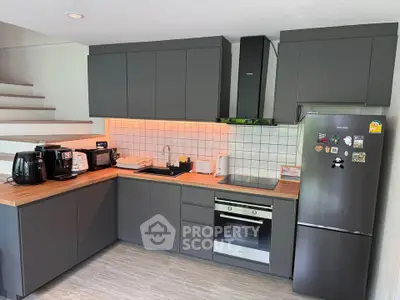 Modern kitchen with sleek cabinetry, built-in oven, and stainless steel fridge in stylish home.