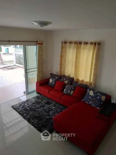 Spacious living room with red sectional sofa and large windows opening to a balcony.