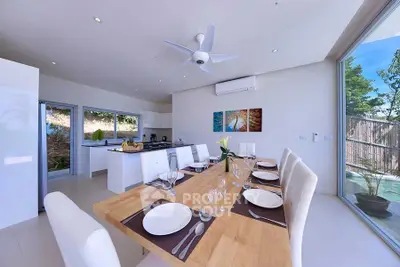 Modern dining area with open kitchen and large windows offering natural light