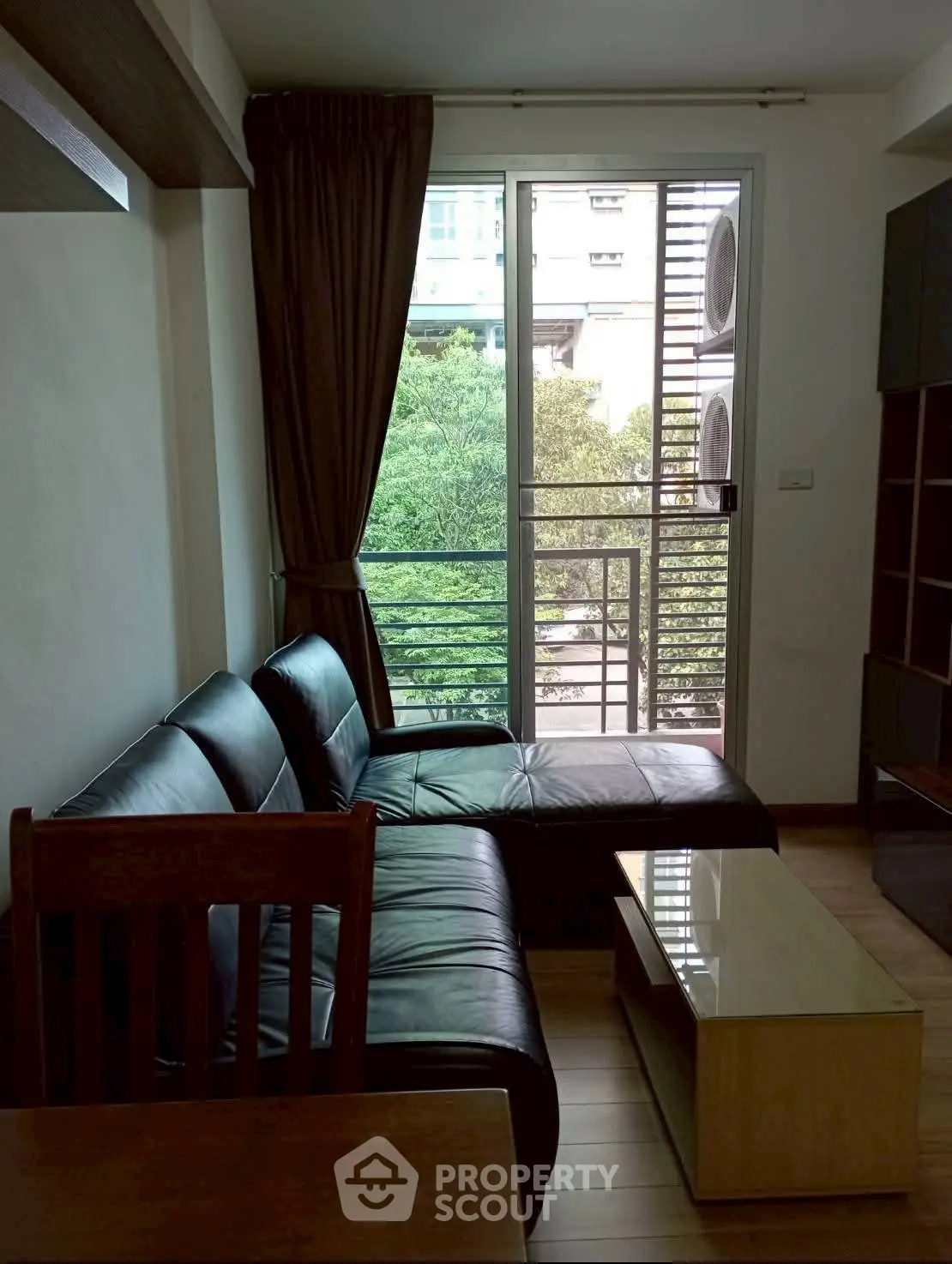 Cozy living room with black leather sofa and balcony view