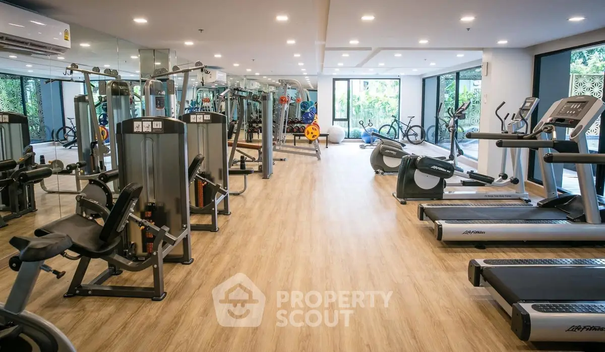 Spacious modern gym with state-of-the-art equipment and large windows for natural light.