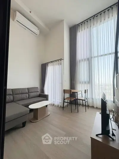 Spacious modern living room with high ceilings and large windows offering natural light.