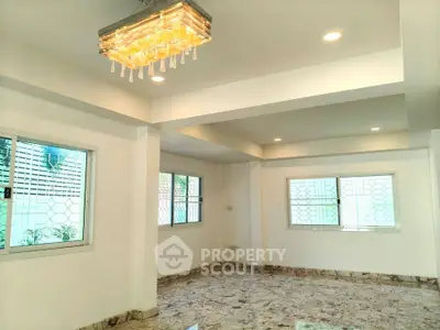 Spacious living room with elegant chandelier and large windows in modern home.