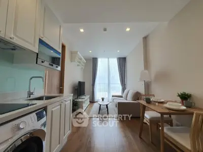 Modern open-plan living room with kitchen and dining area, featuring stylish furniture and natural light.