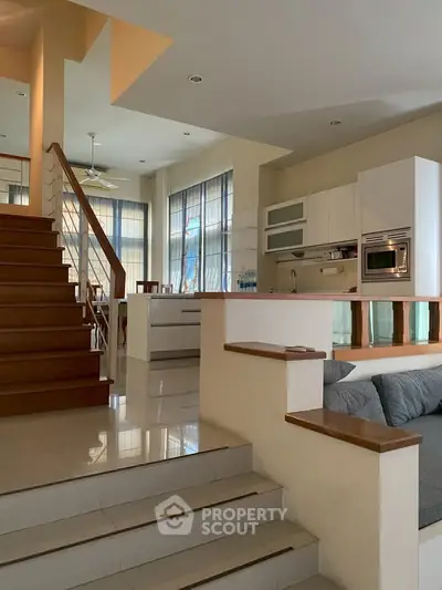 Spacious modern living area with open kitchen and stylish staircase, perfect for contemporary living.